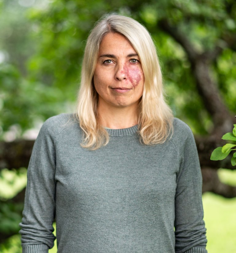 Klimaforsker Reidun Gangstø med blondt hår og grønn natur i bakgrunn. 